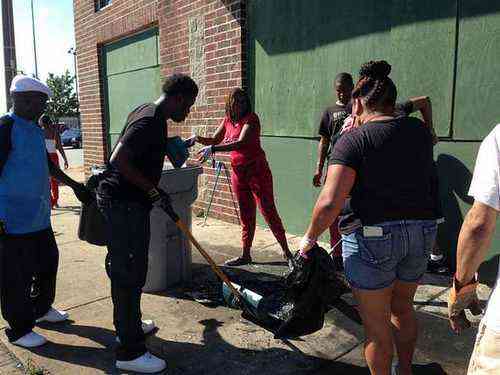 Volunteers sweep and pick up debris, Sunday, Aug. 14, 2016, in a north Milwaukee neighborhood that was rocked by hours of late night violent unrest sparked by a police officer's shooting of a man fleeing a traffic stop. (AP Photo/Gretchen Ehlke)